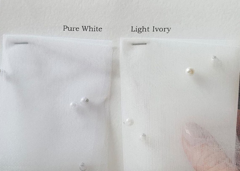 May include: Two swatches of tulle fabric, one labeled "Pure White" and the other "Light Ivory". Both swatches have small pearl-like embellishments.