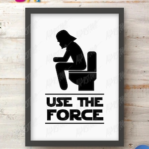 May include: A framed wall art print featuring a black silhouette of a character wearing a helmet sitting on a toilet. Below the figure, the text "USE THE FORCE" is printed in bold, black, block-style capital letters between two horizontal lines.