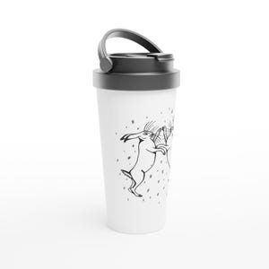 Peut inclure: Mug de voyage blanc avec couvercle et anse noirs. Le mug présente une illustration en noir et blanc de deux lapins dansant parmi de petites formes en forme d'étoiles. Le motif est imprimé sur le corps blanc du mug.