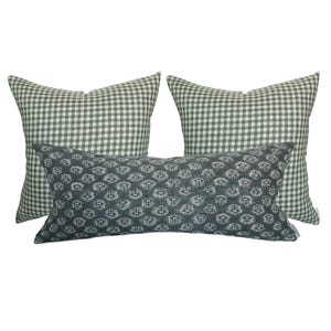 May include: Three decorative throw pillows, two are square and one is rectangular. The square pillows are a green and white gingham pattern. The rectangular pillow is a dark blue with a white floral pattern.