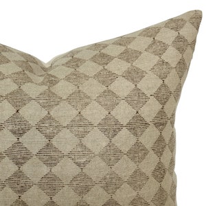 May include: A beige throw pillow with a brown diamond pattern.