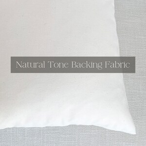 May include: Close-up of a white cotton fabric with the text "Natural Tone Backing Fabric" printed on it.