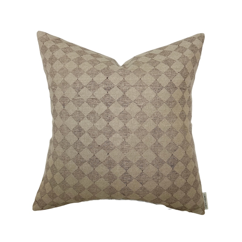 May include: A beige throw pillow with a brown diamond pattern. The pillow is made of a soft, textured fabric.