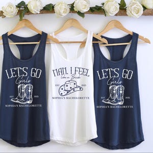 Puede incluir: Tres camisetas sin mangas con un tema de despedida de soltera. La camiseta blanca dice "Man, I feel like a bride" con un gr&aacute;fico de sombrero de vaquero. Las dos camisetas azul marino dicen "Let's go girls" con un gr&aacute;fico de un par de botas de vaquero. Las tres camisetas sin mangas tienen el texto "Sophia's Bachelorette" impreso en ellas.
