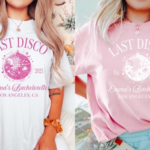 May include: Two white t-shirts with the text "Last Disco" in pink lettering. The shirts feature a pink disco ball graphic and the text "Emma's Bachelorette" with the location "Los Angeles, CA".