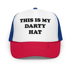 May include: A white trucker hat with a red bill and blue mesh back. The hat has black text that reads "THIS IS MY DARTY HAT".