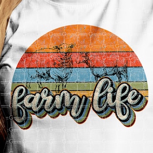 Puede incluir: Una camiseta blanca con un gr&aacute;fico de puesta de sol de estilo retro con tres ovejas y el texto "farm life" en una fuente colorida y estilizada.