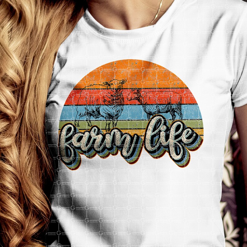 Puede incluir: Una camiseta blanca con un gr&aacute;fico de puesta de sol de estilo retro con tres ovejas y el texto "farm life" en una fuente colorida y estilizada.