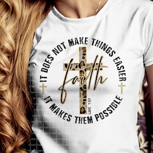 May include: White t-shirt with a black and gold graphic design featuring a leopard print cross and the text "Faith It does not make things easier + It makes them possible Luke 1:37"
