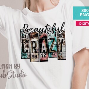 May include: A white t-shirt with a graphic design of the word "Beautiful" above the word "CRAZY" in a vintage license plate style. The design is in shades of blue, green, pink, and brown. The text "DESIGN BY Gsub Studio" is at the bottom of the shirt.