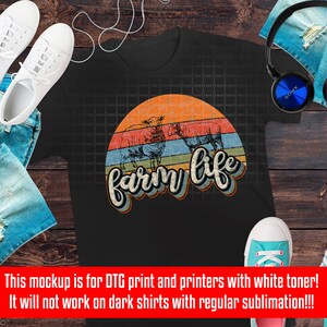 Puede incluir: Una camiseta negra con un gr&aacute;fico de estilo vintage de una puesta de sol con el texto "farm life" en una fuente retro colorida. El gr&aacute;fico presenta tres siluetas de ovejas.