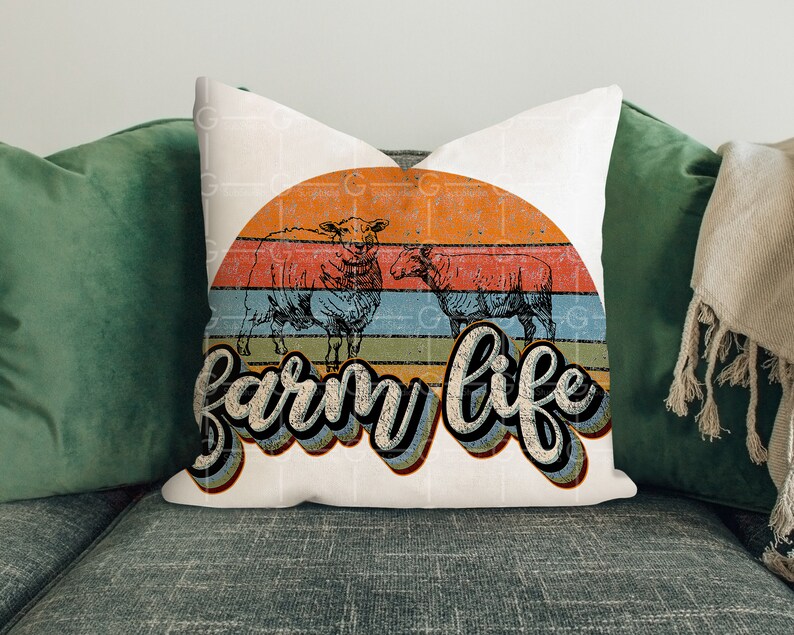Puede incluir: Almohada blanca con un gr&aacute;fico de estilo vintage de dos ovejas frente a una puesta de sol con el texto "farm life" en una fuente retro.