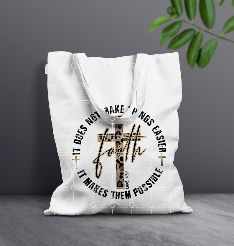 May include: White tote bag with a black circle design featuring a cross with a leopard print pattern and the text "Faith does not make things easier, it makes them possible" and the scripture reference "Luke 1:37".