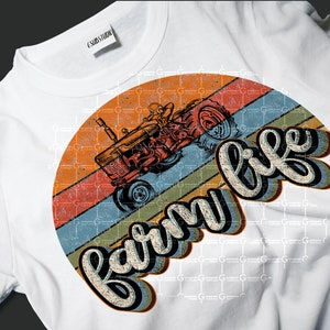 May include: A white t-shirt with a vintage-style graphic of a red tractor in front of a sunset with the text "farm life" in a retro font.
