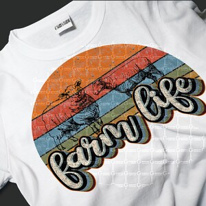 Puede incluir: Una camiseta blanca con un gr&aacute;fico de estilo vintage de tres ovejas y el texto "farm life" en un arco&iacute;ris colorido.