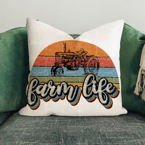 May include: White throw pillow with a vintage-style graphic of a red tractor driving through a sunset with the text "farm life" in a retro font.