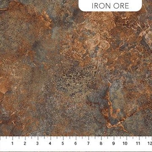 Puede incluir: Primer plano de una tela con apariencia marmolada en tonos marrón, óxido y gris. La tela tiene un aspecto texturizado con una regla a lo largo del borde inferior, que muestra medidas en pulgadas. El texto "IRON ORE" está en la esquina superior derecha.