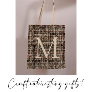 May include: A brown and black tote bag with a white letter "M" on the front. The bag has a woven texture.