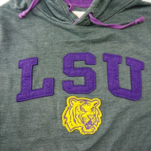 May include: Gray hooded sweatshirt with a purple LSU logo and a yellow tiger mascot.