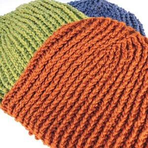 May include: A crocheted beanie hat in three colors: orange, green, and blue. The hat is made with a thick yarn and has a ribbed texture.