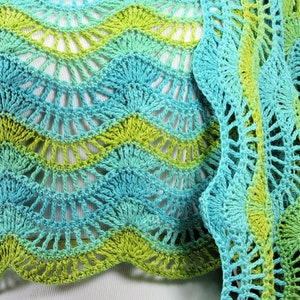 May include: A crocheted shawl in shades of green and blue. The shawl has a scalloped edge and a delicate, lacy pattern.