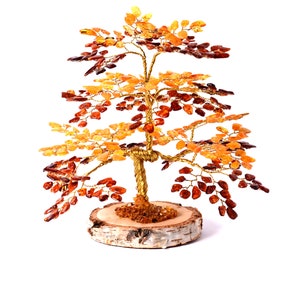 Puede incluir: Una escultura decorativa de árbol con un tronco y ramas de alambre dorado. Las hojas son de color ámbar y el árbol se asienta sobre una base de madera. El árbol mide aproximadamente 20 cm de altura.
