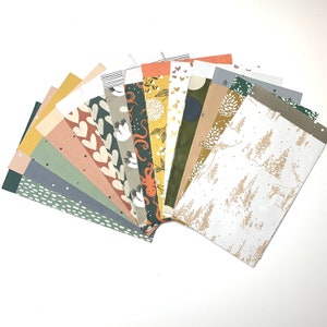 Könnte beinhalten: Eine Sammlung von 16 gemusterten Papieren in verschiedenen Farben und Designs, darunter Herzen, Vögel und geometrische Muster. Die Papiere sind fächerförmig angeordnet, wobei die Spitze des Fächers nach rechts zeigt.