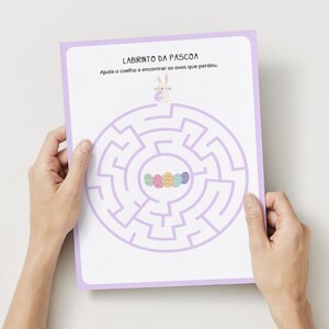 May include: A printable Easter maze activity sheet with a purple border. The maze features a bunny rabbit at the top and a line of colorful Easter eggs at the center. The text "Labirinto da Pascoa" and "Ajuda o coelho a encontrar os ovos que perdeu" is printed at the top of the sheet.