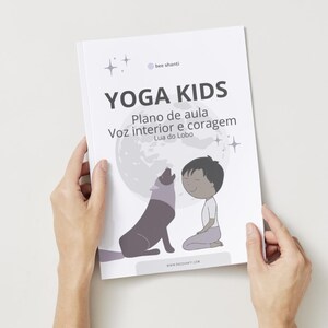 May include: A book titled "YOGA KIDS" held by hands. The cover features a cartoon illustration of a wolf howling at the moon, with a child kneeling nearby. Text includes "Plano de aula", "Voz interior e coragem", and "Lua do Lobo".