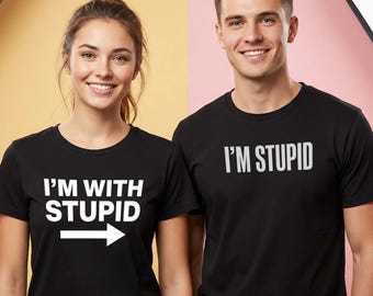 Może przedstawiać: Dwie osoby ubrane w czarne koszulki z białym napisem. Jedna koszulka głosi "I'M WITH STUPID" ze strzałką w prawo. Druga koszulka głosi "I'M STUPID". Tło jest podzielone na żółty i różowy.