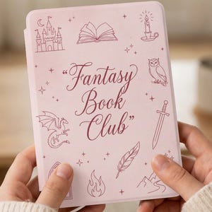 May include: A light pink e-reader case with the words "Fantasy Book Club" in a decorative font. The case is adorned with line drawings of a castle, dragon, owl, sword, and other fantasy-themed elements.