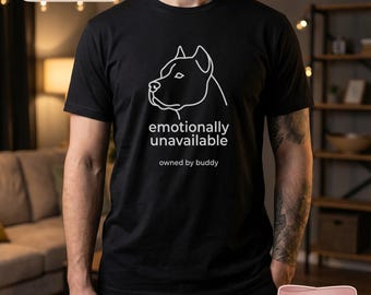Op de afbeelding: Zwart T-shirt met een witte omtrek van een hondenkop en de tekst "emotionally unavailable" en "owned by buddy". Het shirt heeft ook de tekst "Custom Pet Photo Portrait" en "Front and Back Print Available".