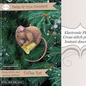 May include: A cross-stitch pattern featuring a heart-shaped mouse with a piece of cheese. The mouse is in shades of brown and tan, with a pink tail. The image includes the text "Toffee Rat" and "Cross stitch and sewing pattern".