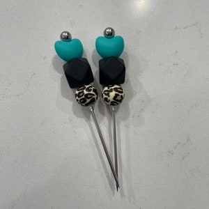 以下が含まれることがあります： ターコイズ、ブラック、レオパード柄のビーズが付いたシルバーの cocktail picks が2本