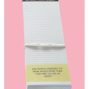 Könnte beinhalten: Ein weißer Notizblock mit schwarzen Linien und einer schwarzen Kopfzeile, auf der "SPRAIN YOUR BRAIN" steht. Der Notizblock hat einen gelben Haftnotiz am unteren Rand, auf dem "ARE PEOPLE DESIGNED TO WEAR SHOES MORE THAN THEY ARE TO LIVE IN ZOOS?" steht.