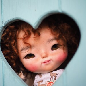 a close up of a doll in a heart shaped hole
