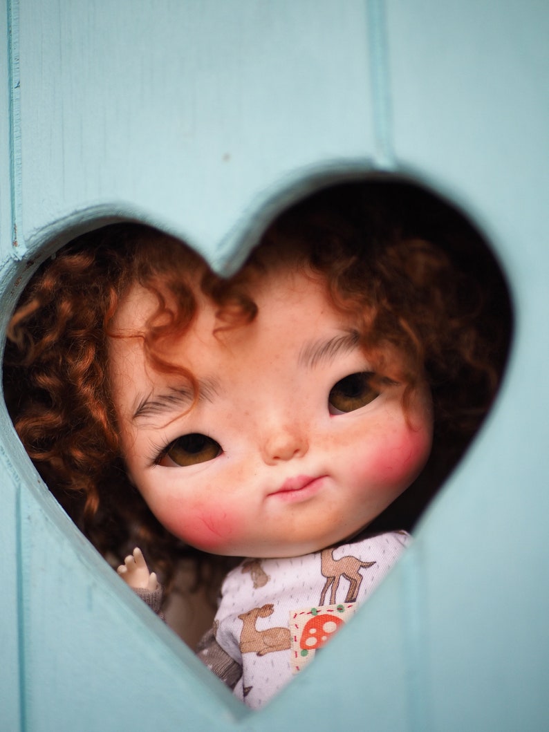 a close up of a doll in a heart shaped hole