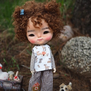 a doll with curly hair standing next to a small dog