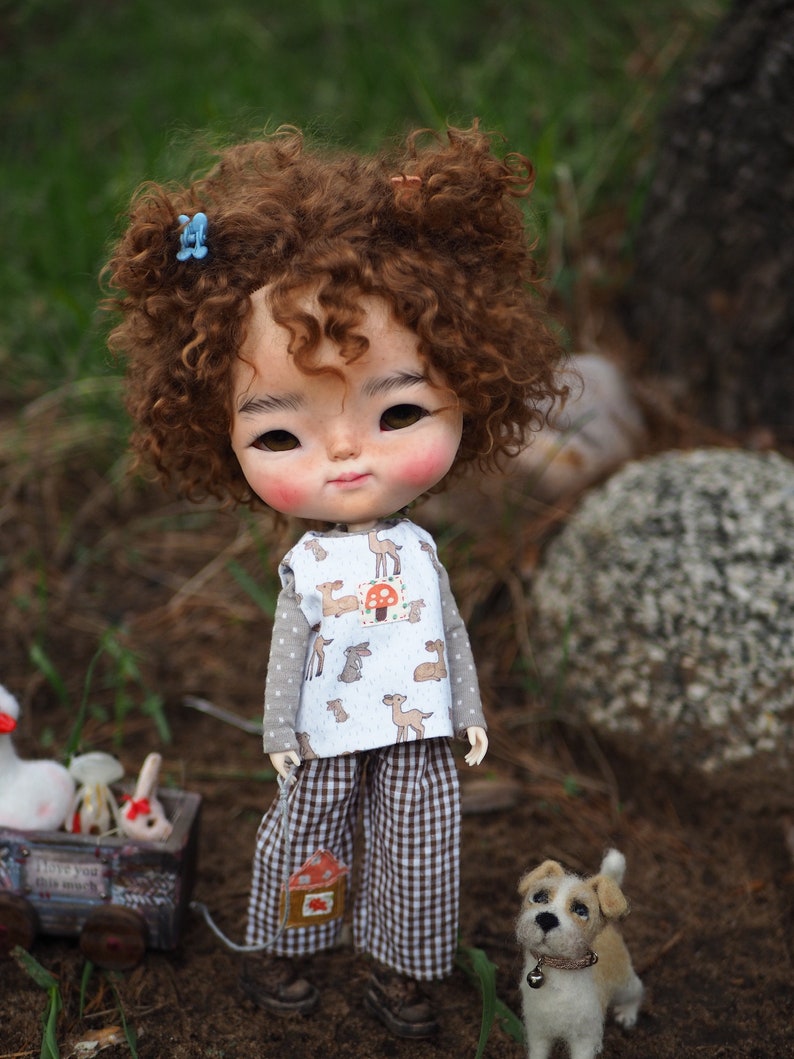 a doll with curly hair standing next to a small dog
