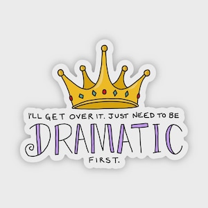 May include: A sticker featuring a gold crown with red and blue gems. The text reads "I'LL GET OVER IT. JUST NEED TO BE DRAMATIC FIRST." The word "DRAMATIC" is in purple, and the rest of the text is black.