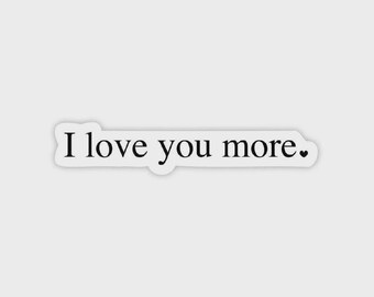 May include: A white sticker with the phrase "I love you more." in black, sans-serif font. A small black heart is at the end of the phrase. The sticker has a white border.