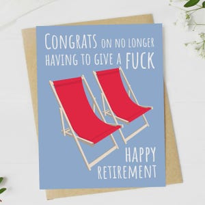 May include: A blue card with the text "Congrats on no longer having to give a fuck Happy Retirement" and two red deck chairs on a blue background.