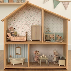 Könnte beinhalten: Ein Puppenhaus aus Holz mit zwei Ebenen und vier Räumen, ausgestattet mit Blumen- und Karotapeten. Das Haus ist eingerichtet mit Miniaturbetten, einem Kleiderschrank, einer Badewanne, einem Küchenherd, einem Tisch, Stühlen und kleinen Mausfiguren.