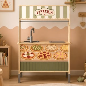 Pode incluir: Uma cozinha de brinquedo de madeira com uma placa de Pizzeria e detalhes de listras verdes e brancas. O painel frontal exibe várias ilustrações de pizzas e a unidade inclui uma torneira e pia cinzas, apoiadas por quatro pernas cinzas.