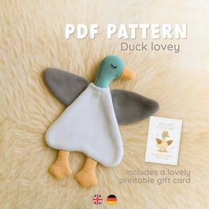 May include: A soft, white and gray duck lovey with a teal head and orange beak. The wings are gray, and the feet are orange. The text "PDF PATTERN Duck lovey" is at the top. Includes a printable gift card.