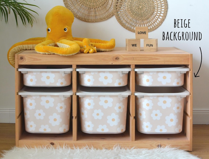 May include: A wooden storage unit with six beige and white floral patterned bins. A large yellow octopus plush toy and a smaller one sit on top. Three wooden blocks spell out "LOVE", "WE", and "FUN".