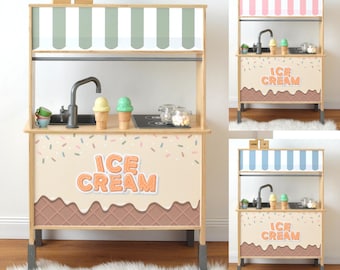May include: A wooden ice cream stand with a striped awning and the words "ICE CREAM" in orange letters. The stand features a sink, toy ice cream cones, and a decorative sprinkle and waffle cone design.