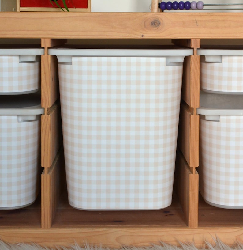 Pu&ograve; includere: Un contenitore rettangolare con un motivo a quadretti vichy beige chiaro e bianco, posizionato all'interno di uno scaffale in legno. Il contenitore presenta un bordo liscio di colore chiaro ed &egrave; affiancato da contenitori simili.