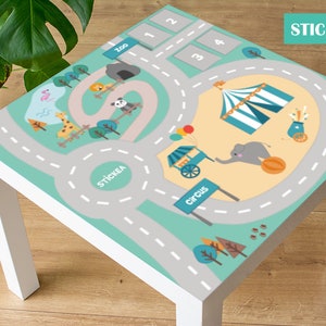 May include: A turquoise and gray play mat sticker with a road, a zoo, a circus, and numbers 1 through 4. The sticker is designed to be placed on a table or other flat surface.