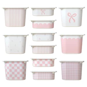 Peut inclure: Une collection de bacs de rangement blancs et roses avec divers motifs. Les motifs comprennent des rayures verticales, des nœuds, des bords festonnés, des imprimés floraux et des motifs à carreaux. Les bacs sont en matériau durable.